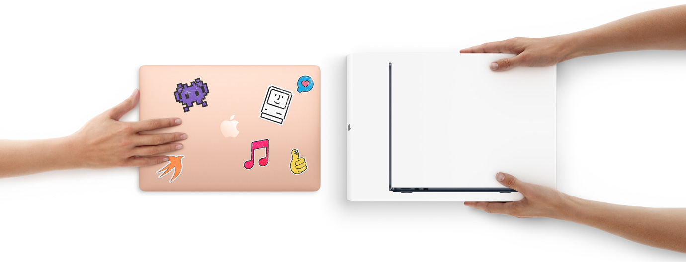 A hand slides a MacBook with stickers on the cover towards two hands holding a new MacBook in the box