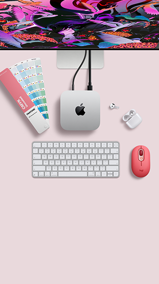 Mac mini, отгоре, сребърен алуминий, заоблени ъгли, гланцирано черно лого на Apple в центъра, свързано с кабел, Studio Display е частично видим отгоре, AirPod 4, отворени, Pantone цветови мостри и цифрова клавиатура, и мишка