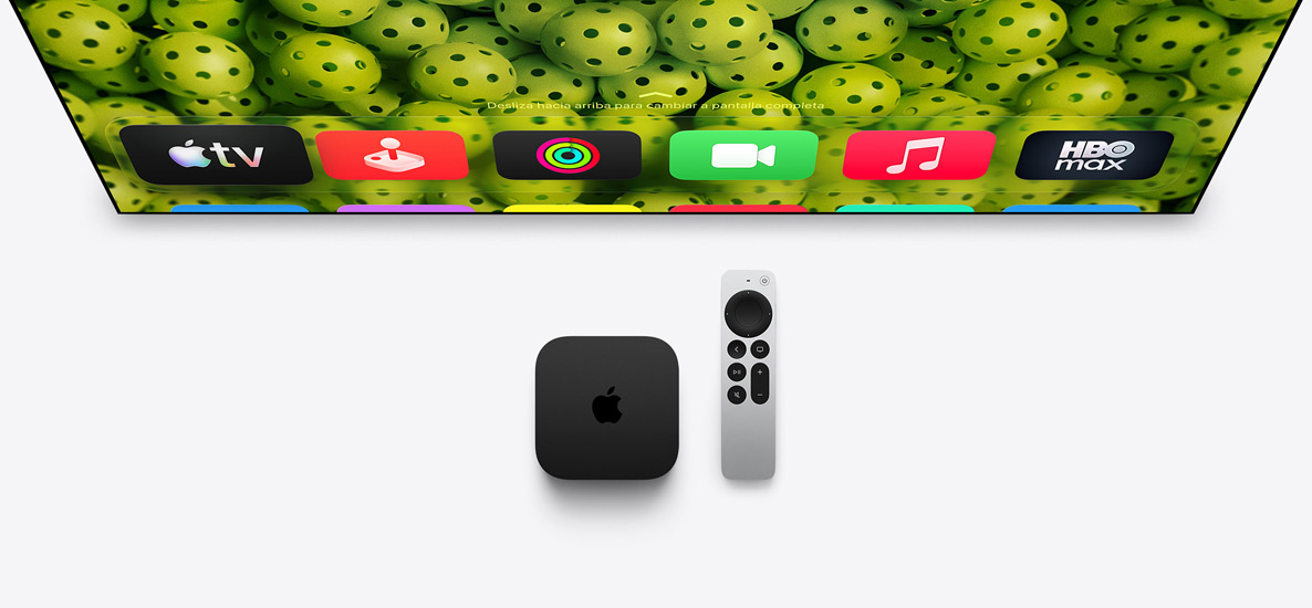 Un Apple TV 4K y un mando Siri Remote debajo de un televisor, la pantalla muestra los iconos de las apps de la pantalla de inicio en la fila superior sobre un fondo verde con pelotas de pickleball
