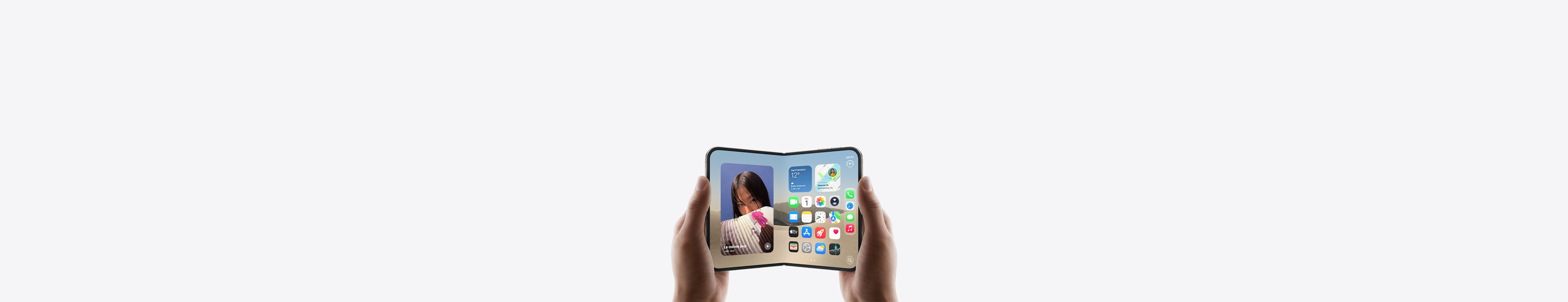 iPhone Duo, finition blanc stellaire, fermé, tenu par une main, montrant l’écran externe qui affiche l’écran d’accueil avec des apps et des widgets.