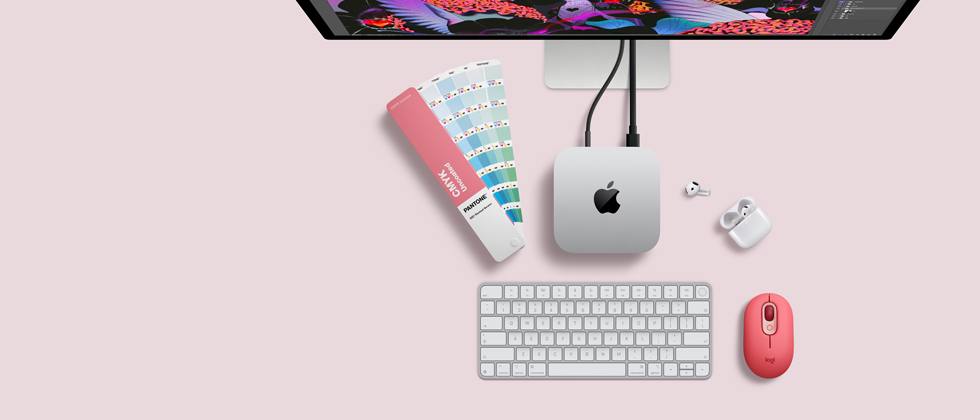 Mac mini, odozgo, srebrni aluminij, zaobljeni uglovi, sjajni crni Appleov logotip u sredini, povezan kabelom, Studio Display djelomično vidljiv odozgo, AirPod 4, otvoren, Pantone skala boja te numerička tipkovnica i miš