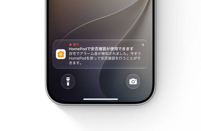 iPhoneのロック画面にホームアプリからの重要な通知が表示されている。テキストで「重大、HomePodで安否確認が使用できます。自宅でアラーム音が検知されました。今すぐHomePodを使って安否確認を行うことができます」と書かれている