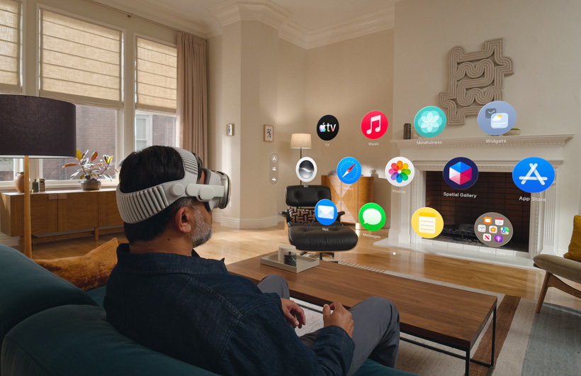 مستخدم يضع Apple Vision Pro وهو جالس على أريكة في غرفة معيشة ويشغّل الواجهة الرئيسية