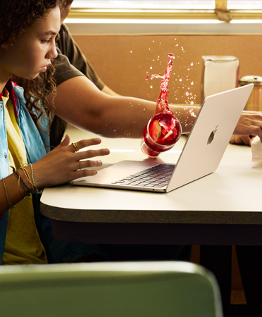 คนเอื้อมหยิบของบนโต๊ะในร้านอาหาร ทำให้เครื่องดื่มเย็นหกใส่ MacBook ที่เปิดอยู่