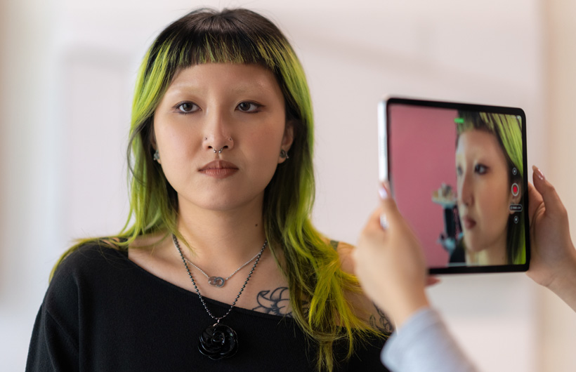 A student with green-tinted hair gets her face scanned with an iPad&nbsp;camera.