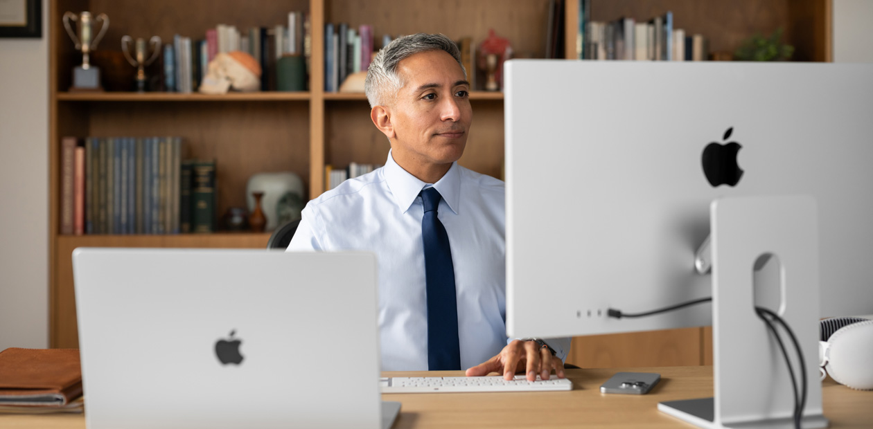 A provider sitting at his desk while looking at an iMac and MacBook&nbsp;Pro.