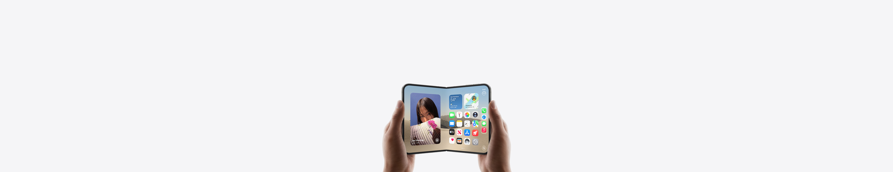 横向きに開いた状態のiPhone Duoを両手で持っている。インナーディスプレイにはホーム画面が表示されている