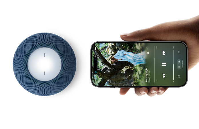 HomePod mini 2 und iPhone: Eine Hand hält ein iPhone neben einen HomePod mini 2 in Blau, um das Feature Handoff zu zeigen