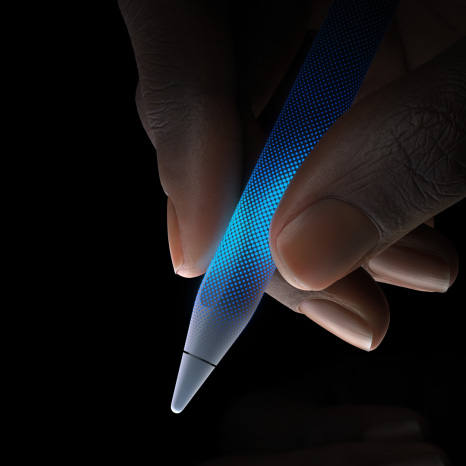 Apple Pencil Pro, vue latérale, blanc, profil fin, revêtement texturé, main tenant l’Apple Pencil avec la pointe orientée vers le bas illustrant la sensibilité tactile et le retour haptique
