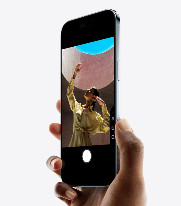 一隻手握著 iPhone Air，拇指按著相機控制按鈕，機身正側面展示纖薄外形、動態島、側邊的按鈕。