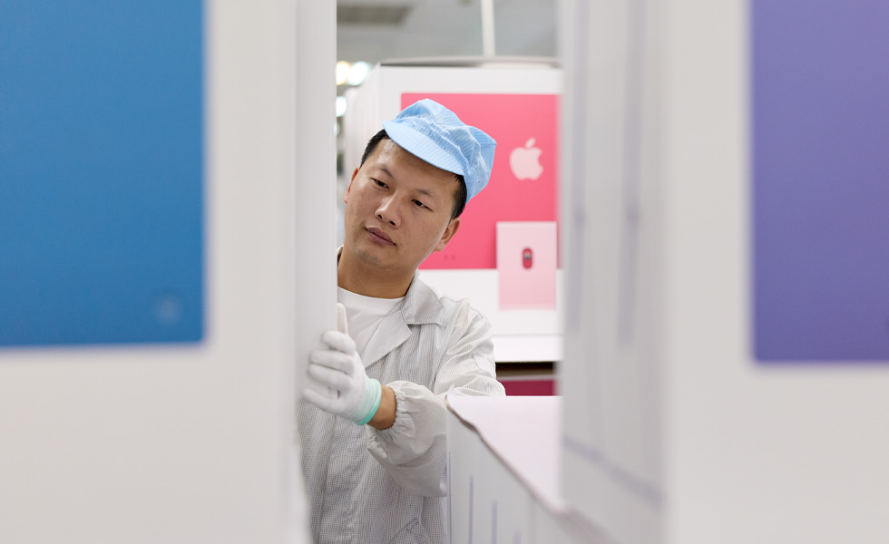 Factory worker wearing protective clothing inspecting equipment inside a manufacturing facility.